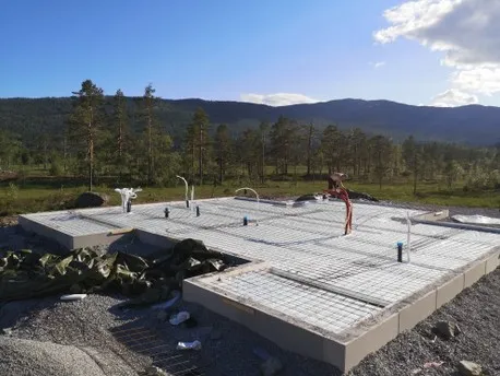 Fresh concrete foundations on a hillside with mountains behind