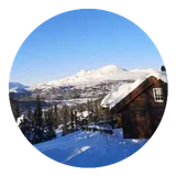 A cabin in the snow with mountains behind